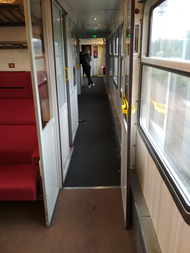 Bild zeigt den sehr schmalen Gang im Zug. Auf der linken Seite befinden sich die einzelnen Zugabteile, auf der rechten Seite befinden sich die Fenster